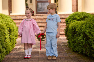 Little English traditional children's clothing.  Long sleeve pink corduroy dress with Christmas motif smocking around the neckline for little girls. Boys blue corduroy set - banded pants paired with Eaton collar short sleeve top with holiday train smocking across the chest.
