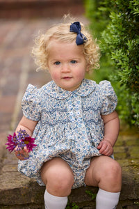 Little English classic children's clothing.  Dressy peter pan bubble for baby girls in blue Wisteria Floral with puff sleeves, ruffle details, and smocking at chest.