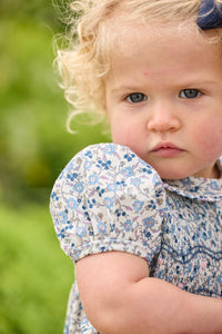 Little English classic children's clothing.  Dressy peter pan bubble for baby girls in blue Wisteria Floral with puff sleeves, ruffle details, and smocking at chest.