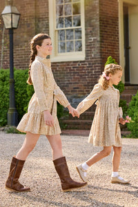 Little English traditional children's clothing. Long sleeve peter pan dress in tan Camden Floral with smocking across the chest for little girls. Older girls shirt dress in tan Camden Floral with long sleeves and tie sash at waist.