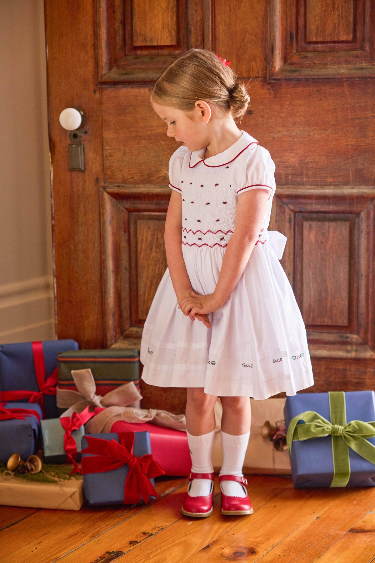 little english classic children's clothing white peter pan collar dress with cap sleeves and smocked detailing with red piping and holly embroidery for girls holiday 