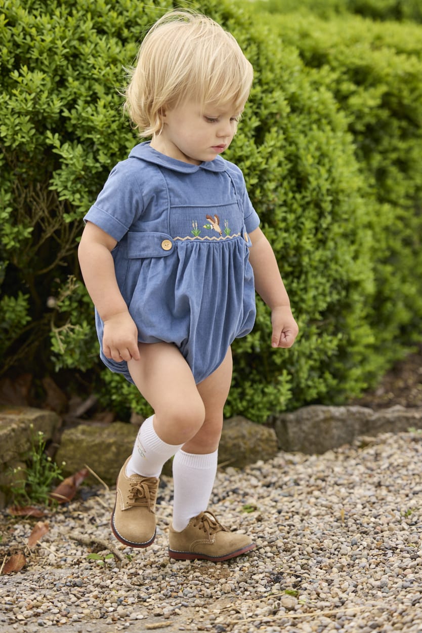 Little English classic children's clothing.  Baby boys stormy blue corduroy peter pan bubble with button tabs and flying mallard smocking across the chest.