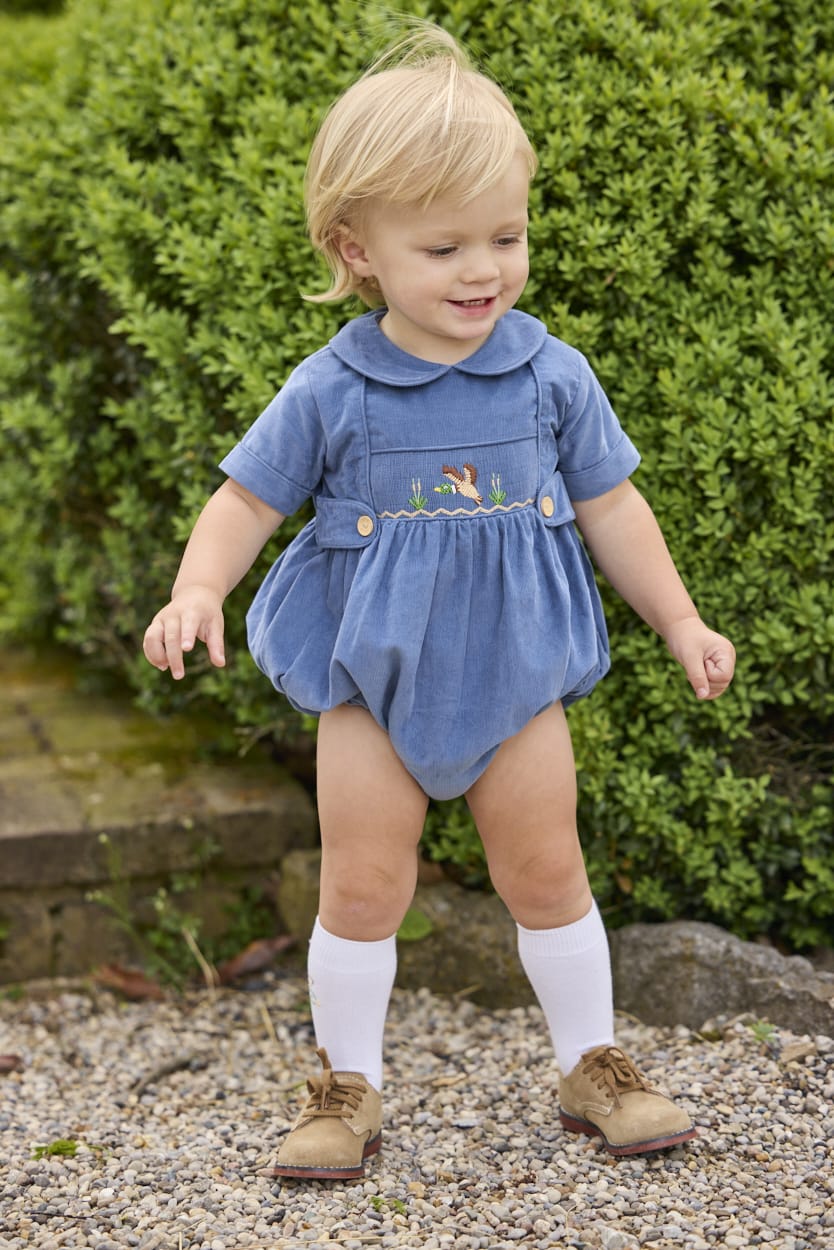 Little English classic children's clothing.  Baby boys stormy blue corduroy peter pan bubble with button tabs and flying mallard smocking across the chest.