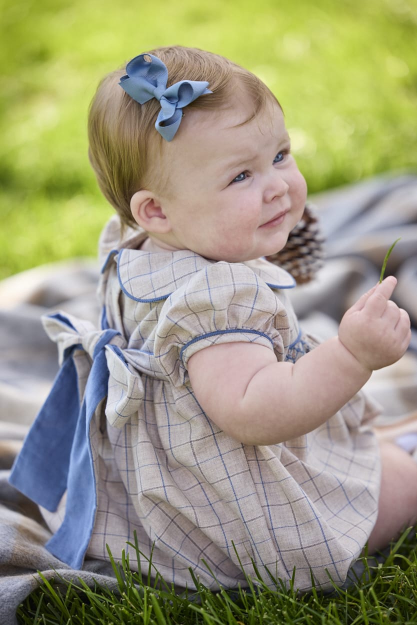 Little English classic children's clothing.  Smocked peter pan bubble in tan and blue Durham windowpane with puff sleeves and blue piping for baby girls