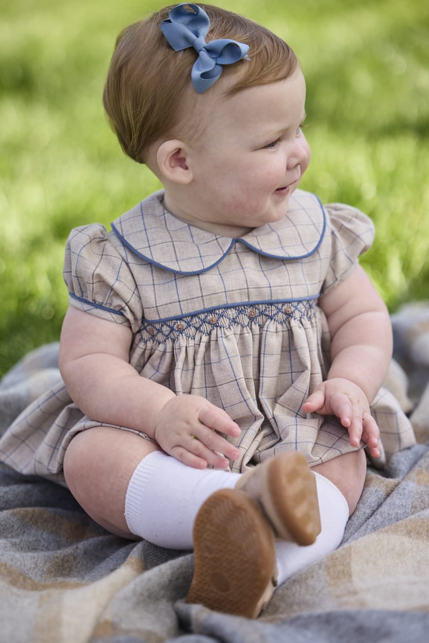 Little English classic children's clothing.  Smocked peter pan bubble in tan and blue Durham windowpane with puff sleeves and blue piping for baby girls