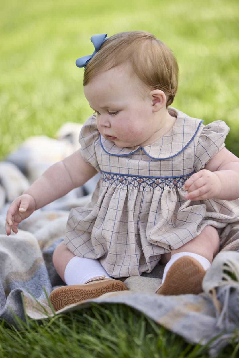 Little English classic children's clothing.  Smocked peter pan bubble in tan and blue Durham windowpane with puff sleeves and blue piping for baby girls