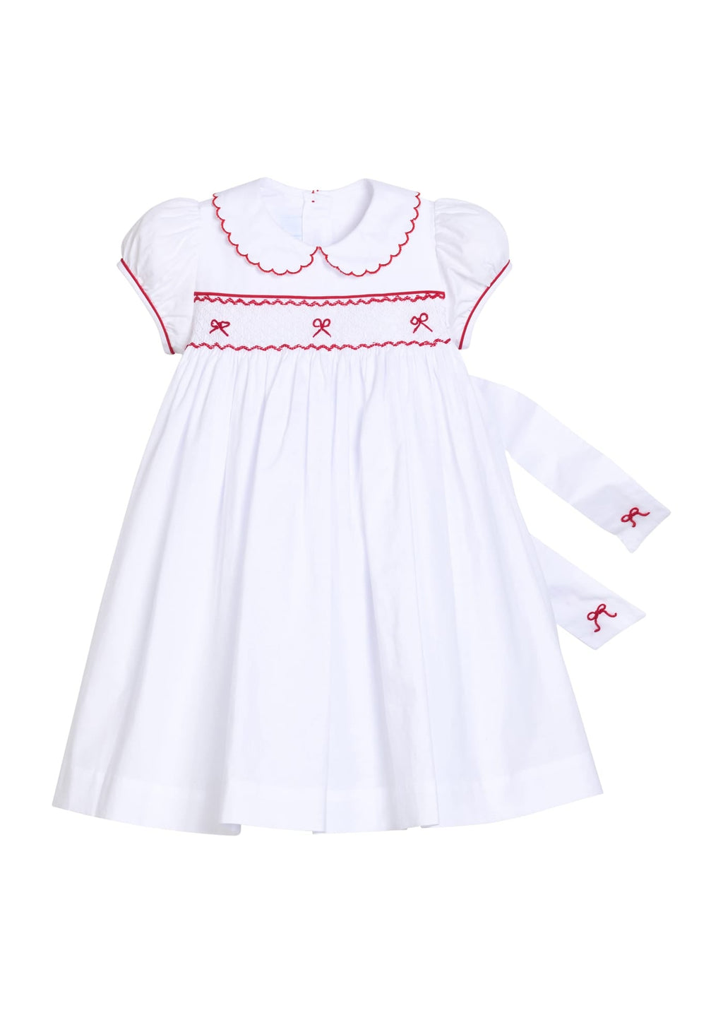 Little English traditional children's clothing.  Puff sleeve white peter pan dress with scalloped collar, red trim, and bow smocking across the chest.  Dressy outfit for little girls for the holiday