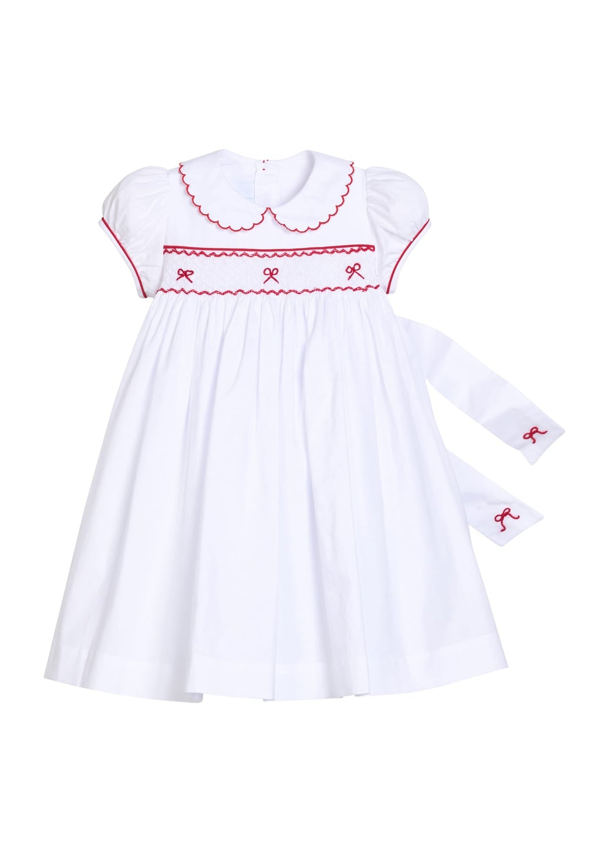 Little English traditional children's clothing.  Puff sleeve white peter pan dress with scalloped collar, red trim, and bow smocking across the chest.  Dressy outfit for little girls for the holiday