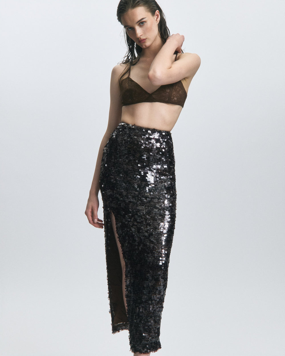 Front view of Midnight Oasis Sequin Skirt showcasing high-waist black sequins and front thigh slit on light gray background