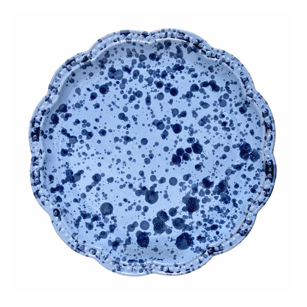 Top-down view of speckled blue dinner plate showcasing scalloped edge and dark navy splatter pattern on white background
