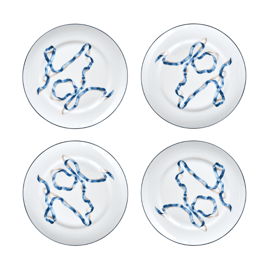 A set of four ribbon dinner plates in Blue. Comprised of a series of ribbon adorned plates, the collection is a delightful departure from traditional holiday decor. The plates are inspired by prints of citrus fruits from the 17th and early 18th centuries showing ribbons bearing the names of the depicted fruit.