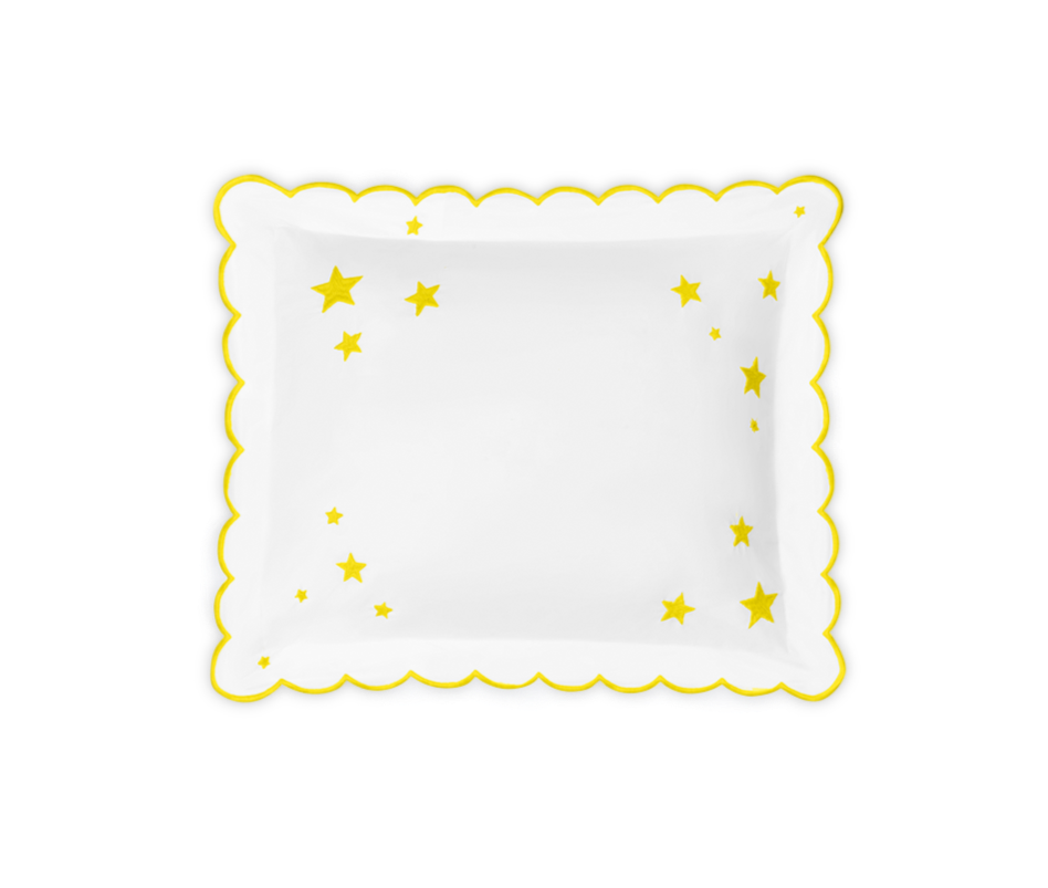 Top view of Stars Mini Pillow showing yellow embroidered stars and scalloped yellow flange on white fabric against black background