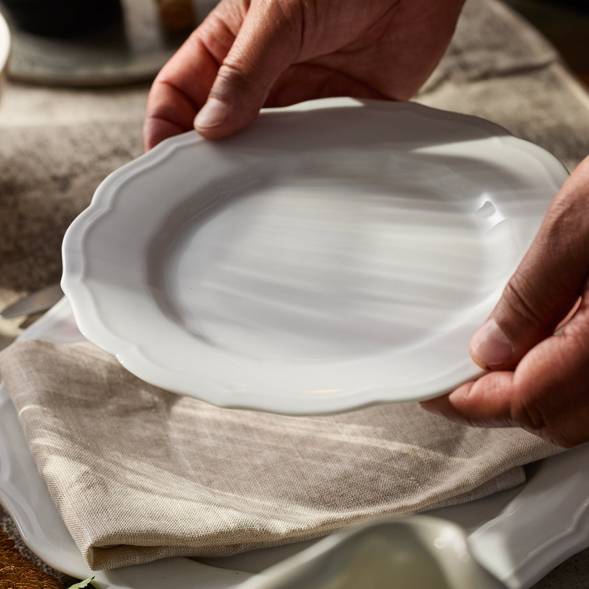 Close-up of Stella scalloped white salad plate showing scalloped edge and glossy finish on a linen napkin