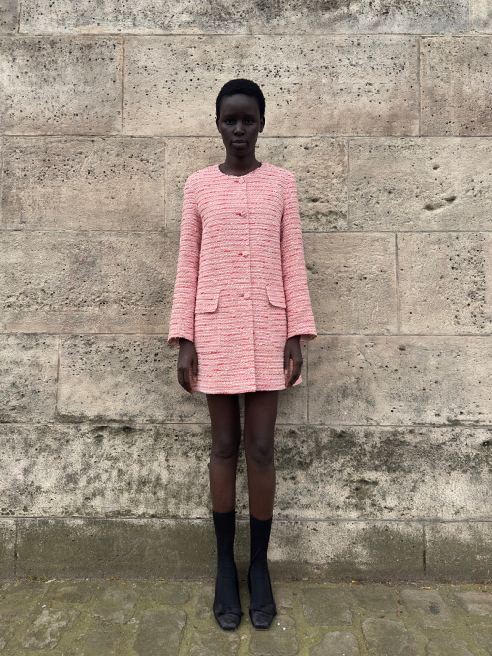 Front view of Stephanie jacket in Rouge Bateau tweed showcasing tweed-covered buttons and front patch pockets against a stone wall