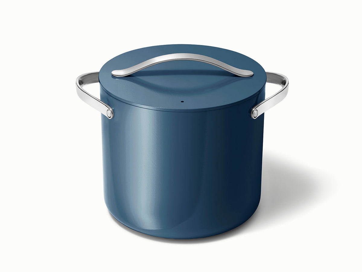 Front three-quarter view of navy stock pot with lid and stainless-steel handles on white background