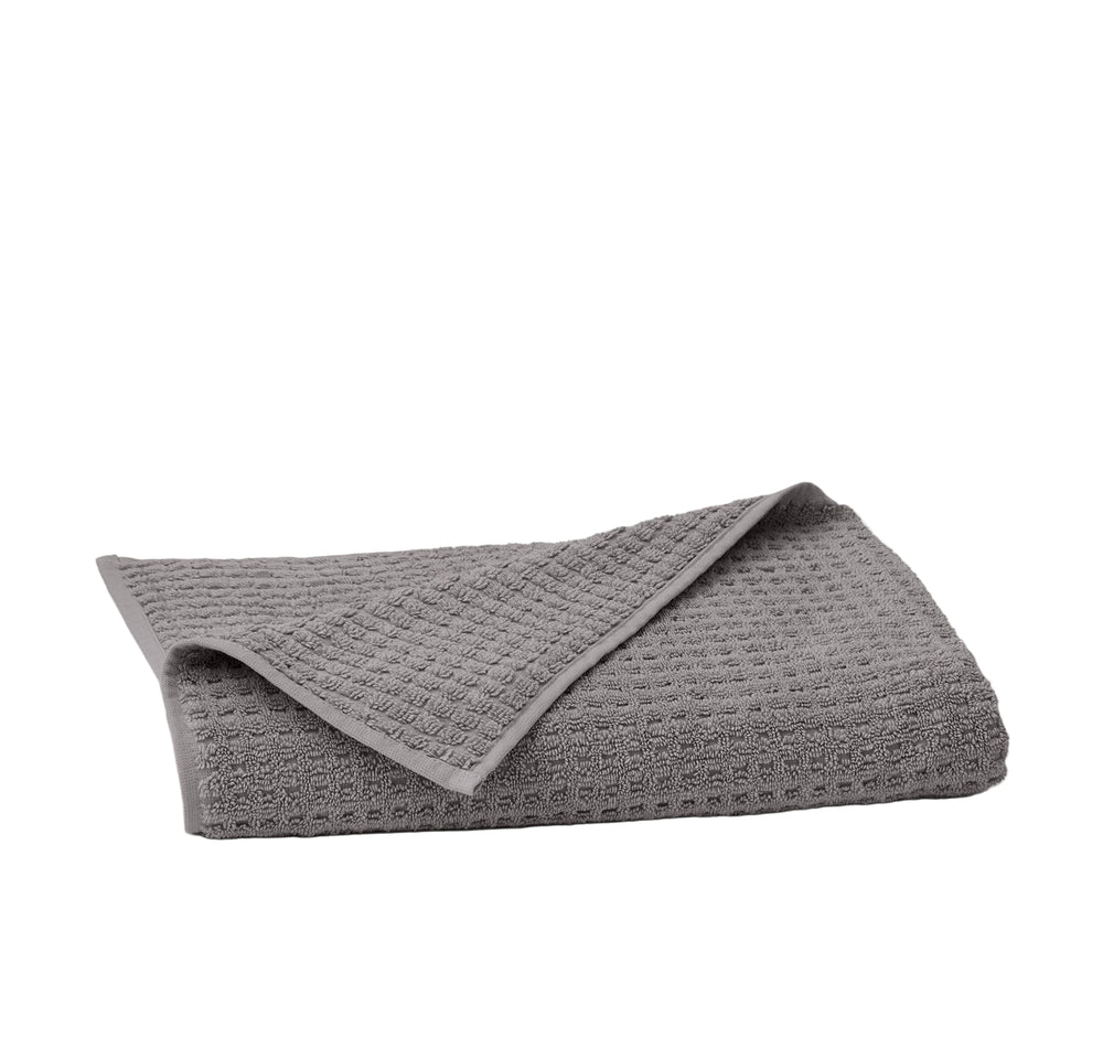 Folded Turkish waffle bath towel in stone showing waffle texture and finished hem on white background
