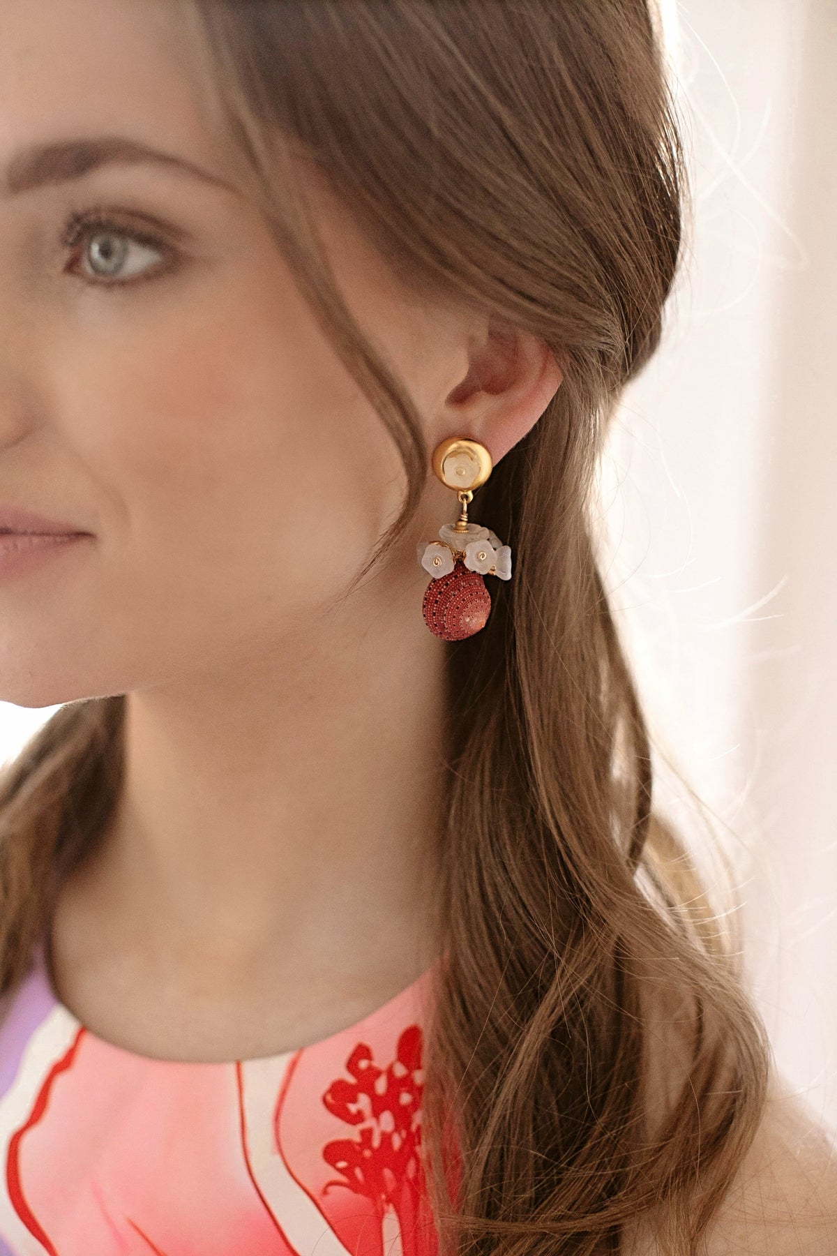 Side view of Strawberry Sunset earrings showing strawberry shell drop, clustered white glass tulip accents, and 24k gold-plated button topper on model