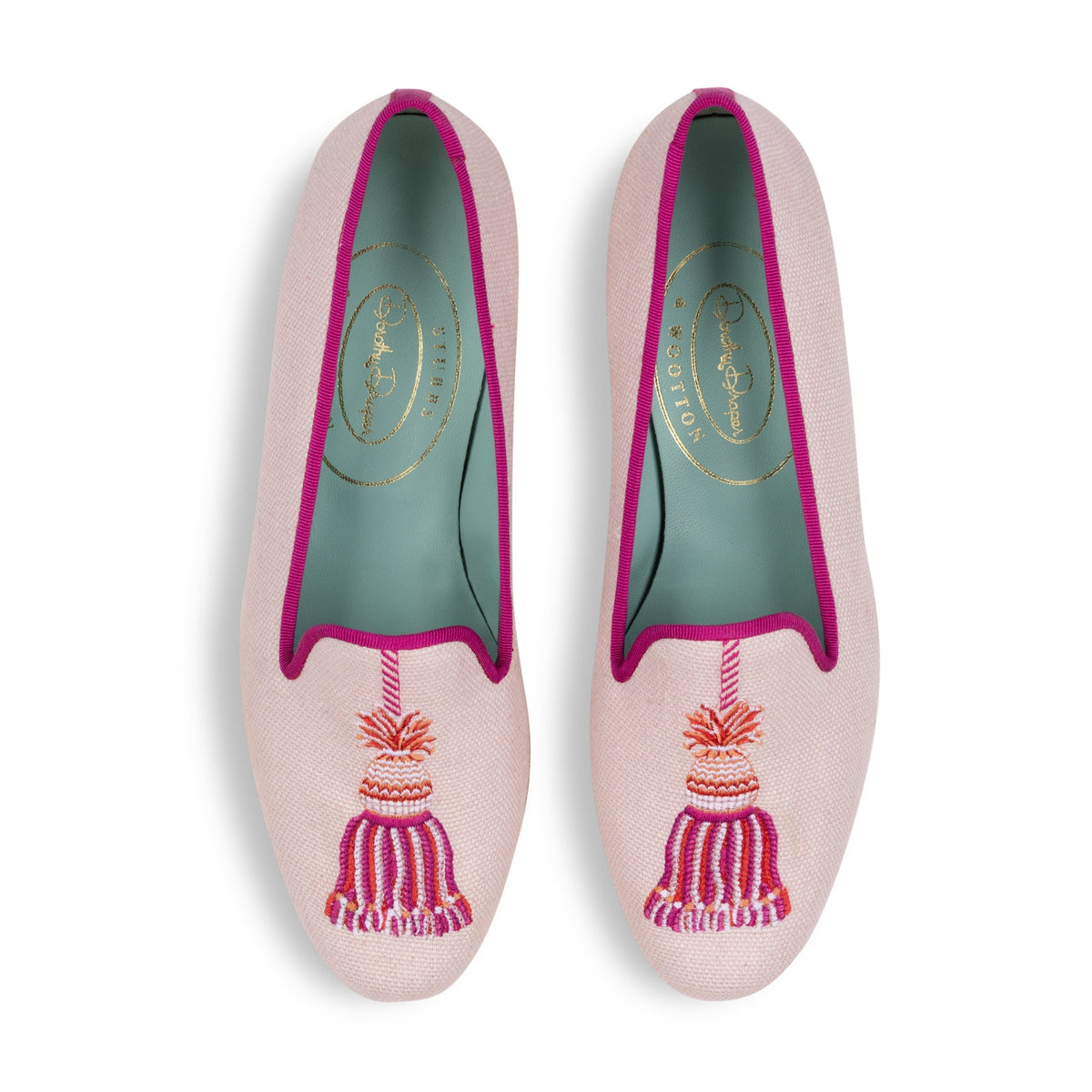 Top view of Tassel Blush linen slippers showcasing embroidered tassels, fuchsia trim, and teal leather lining on white background