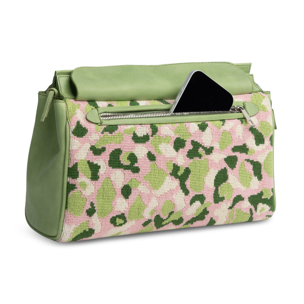Three-quarter view of Hidden Palm Needlepoint Traveler showcasing pink and green camouflage needlepoint and front pocket on white background