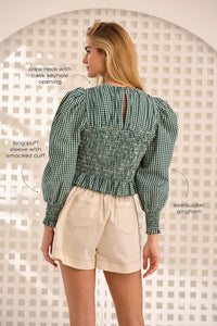 The Eubanks Top has a fitted bodice, puff sleeves, smocked cuffs, shirred yoke, and purl edge trim.