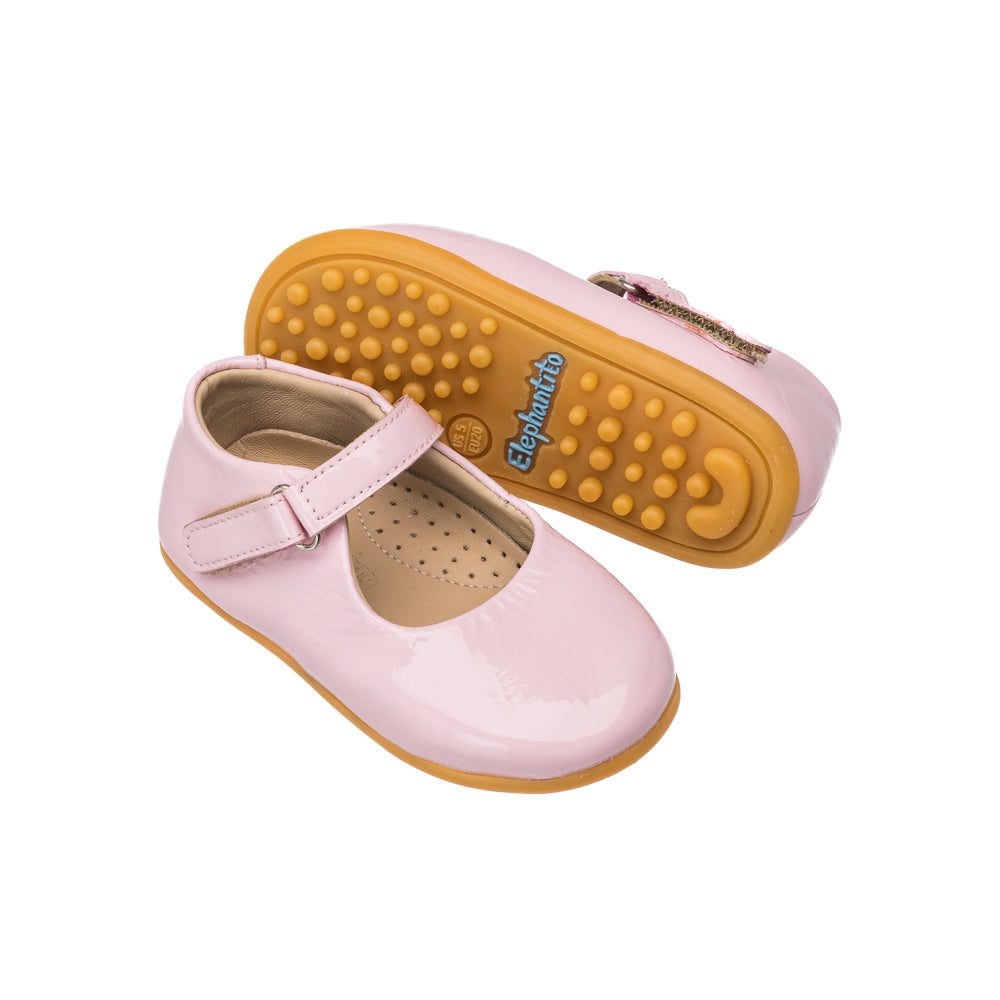 Angled view of Toddler Bare Mary Jane in Pink showcasing cracked patent leather and hook-and-loop strap with white background