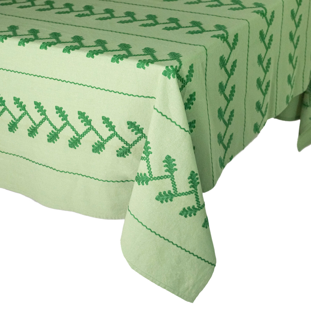 Close-up of Tonal Green Vine Tablecloth with green embroidered vine motifs and scalloped edges on a white background