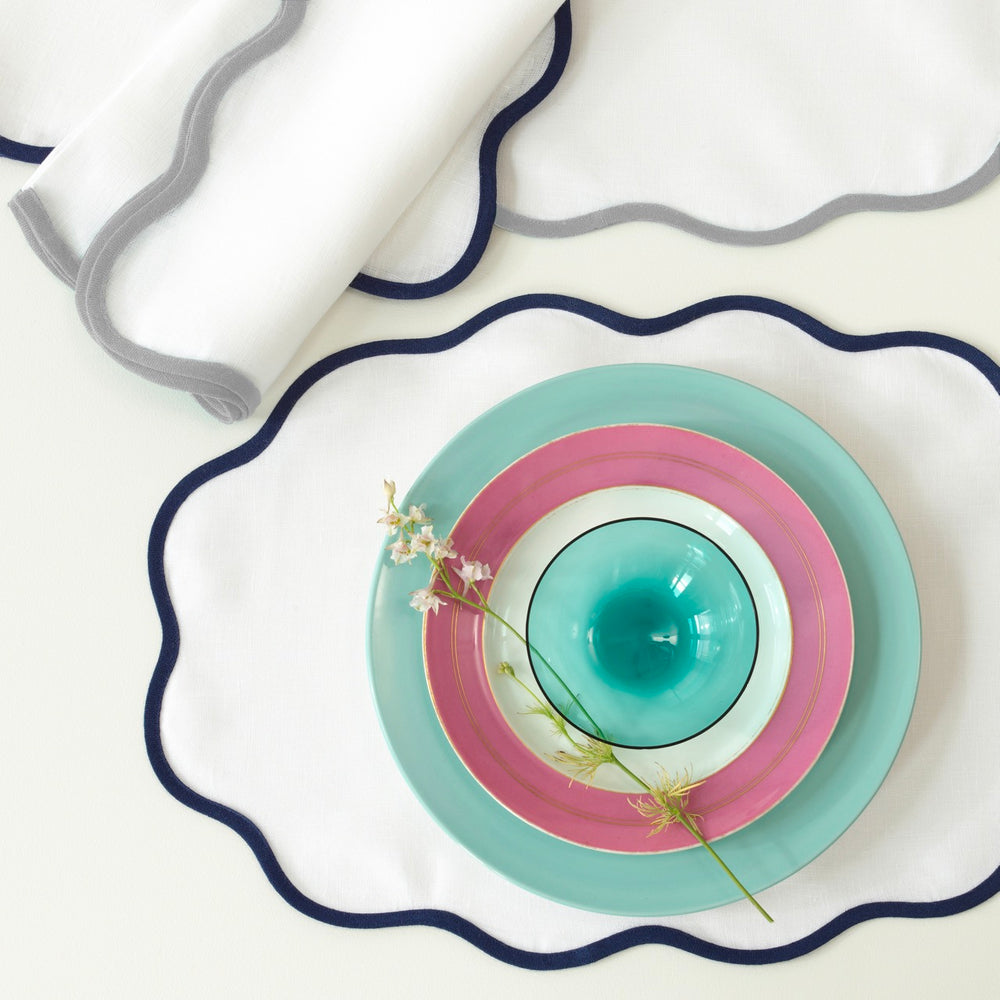 Top view of Scallop Edge Oval placemat showcasing navy scalloped trim on white linen background