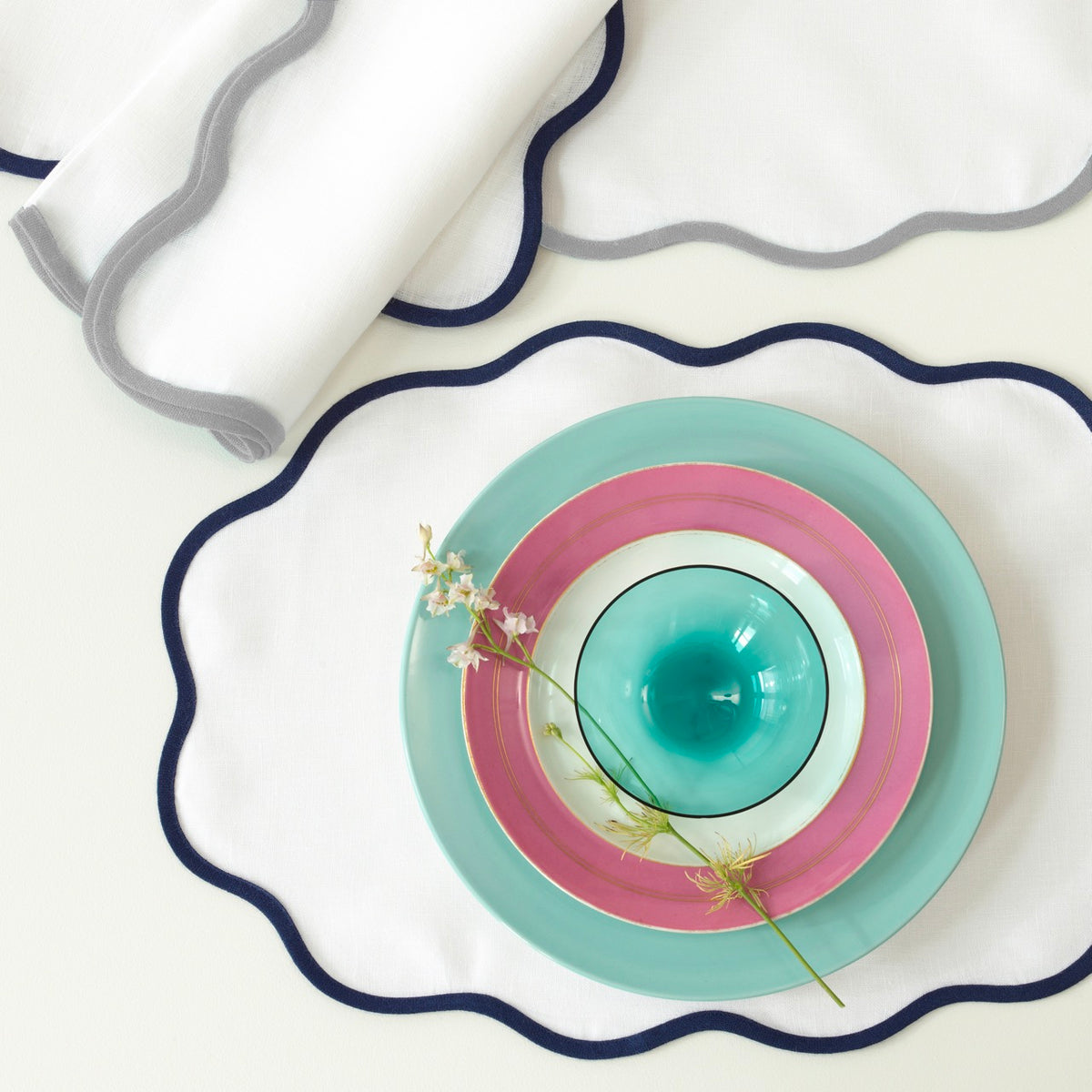 Top view of Scallop Edge Oval placemat showcasing navy scalloped trim on white linen background