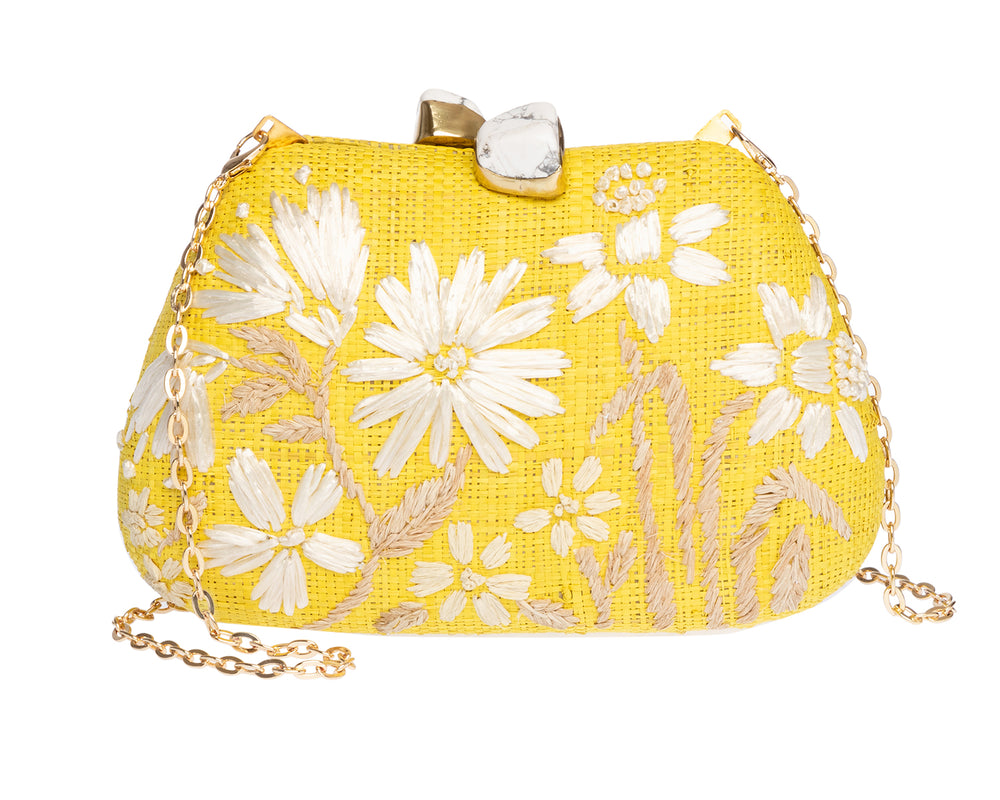 Front view of Tamu Top Handle bag showcasing yellow raffia, white embroidered daisies, marble-look clasp and gold chain strap
