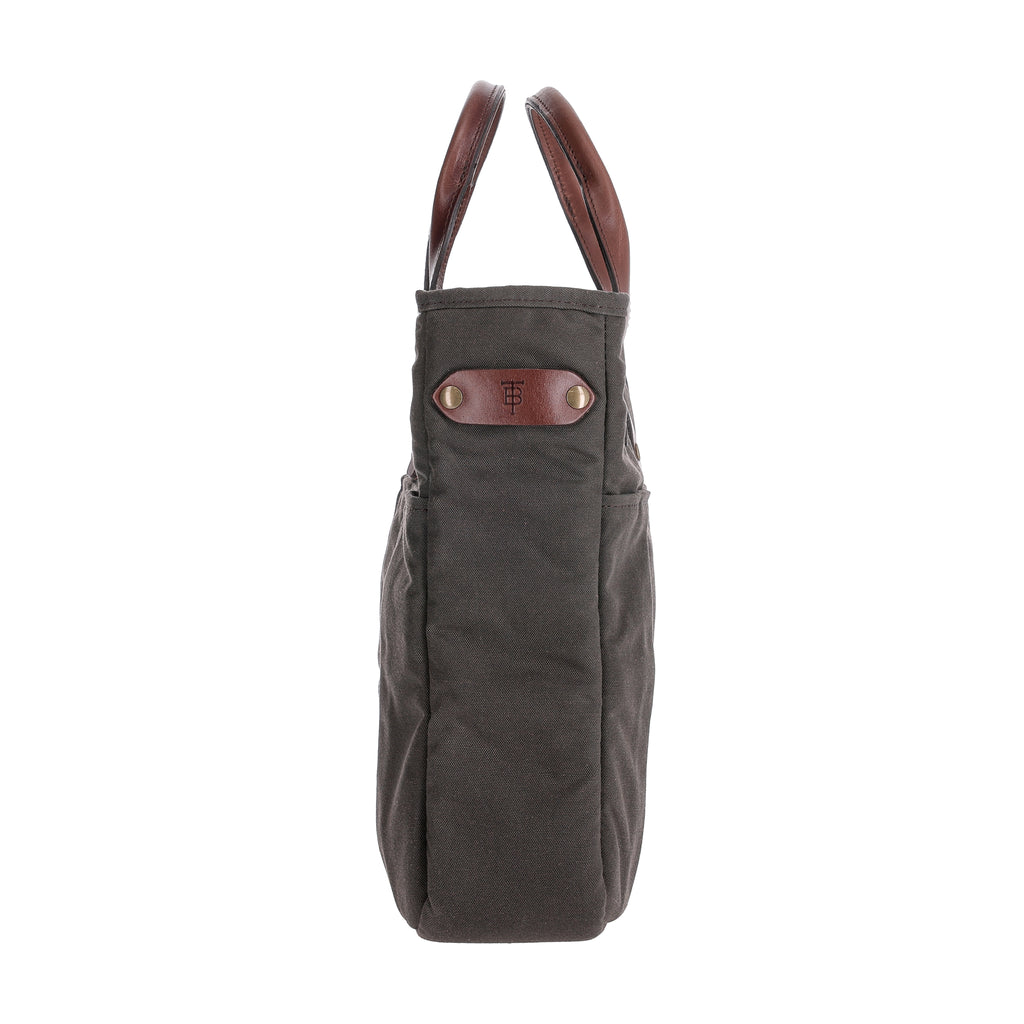 Side view of Bark Canvas Whiskey Tote showcasing leather handles and exterior slip pockets against a white background