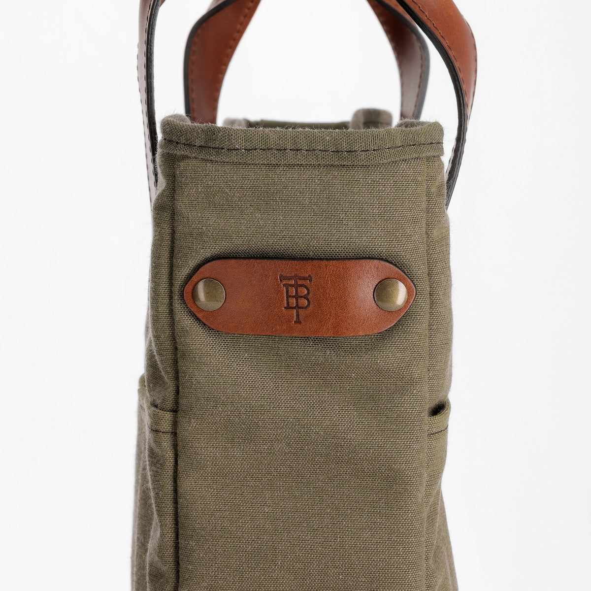 Close-up front view of Sawgrass Canvas Whiskey Tote showcasing leather logo patch and exterior pocket on white background