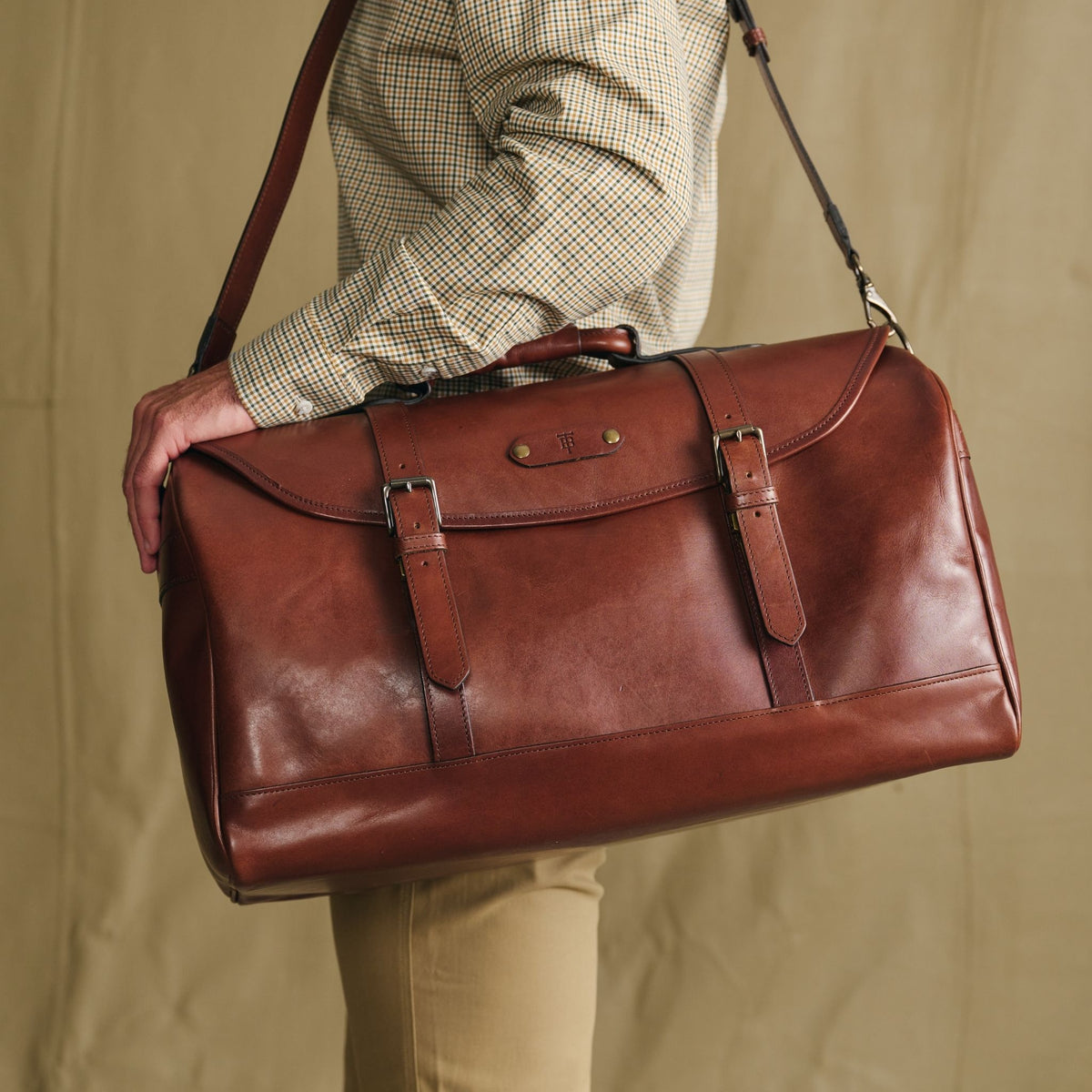Person carrying the Tom Beckbe Leather Weekender Duffel Bag in oak leather over the shoulder
