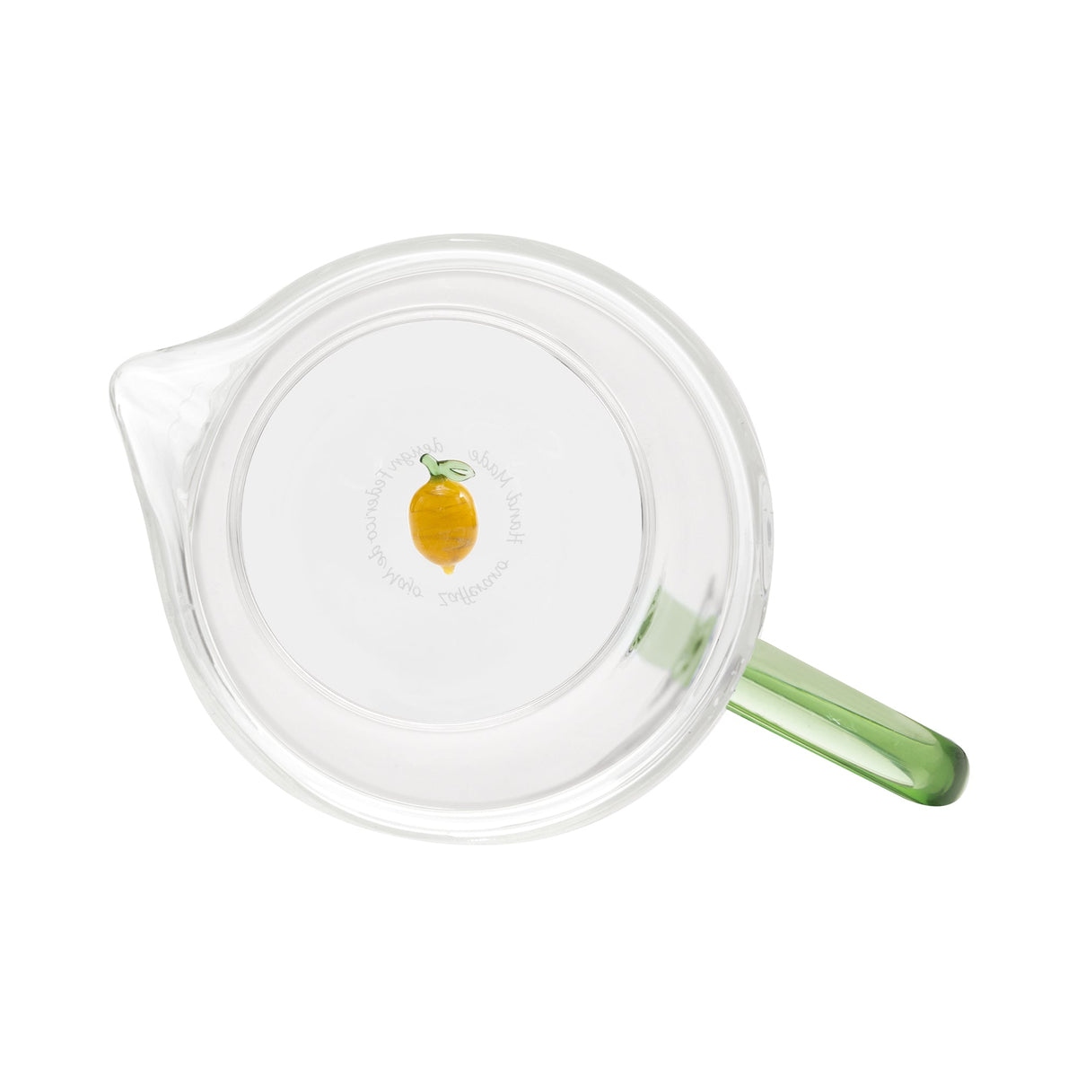 Top view of Teca Frutta glass carafe showing clear body, green handle, and small lemon decoration on white background