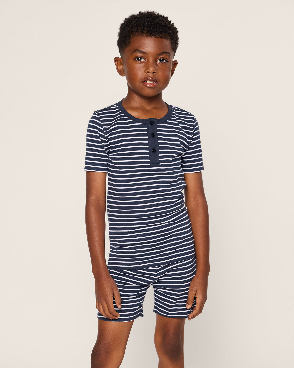 Front view of Kid’s Pima Snug Fit Pajama Short Set in Navy Stripe showcasing button-front top and shorts on a beige background