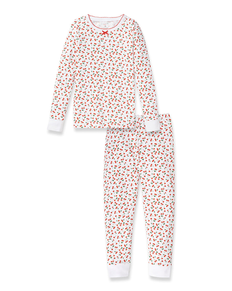 The Petite Plume Kids Pima Snug Fit Pajama Set in Cherry Orchard features a soft white Pima cotton long-sleeve top and bottoms, adorned with red cherry and green leaf print, a charming red bow at the neckline, and finished with red trim.