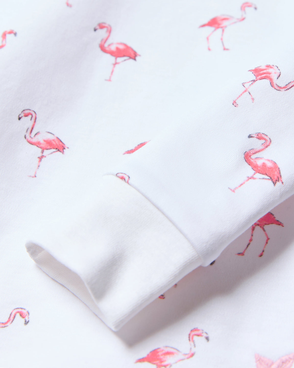 A close-up of soft Pima cotton fabric shows a playful pattern of small pink flamingos, part of Petite Plumes Kids Pima Snug Fit Pajama Set in Flamingo, perfect for a childs wardrobe.