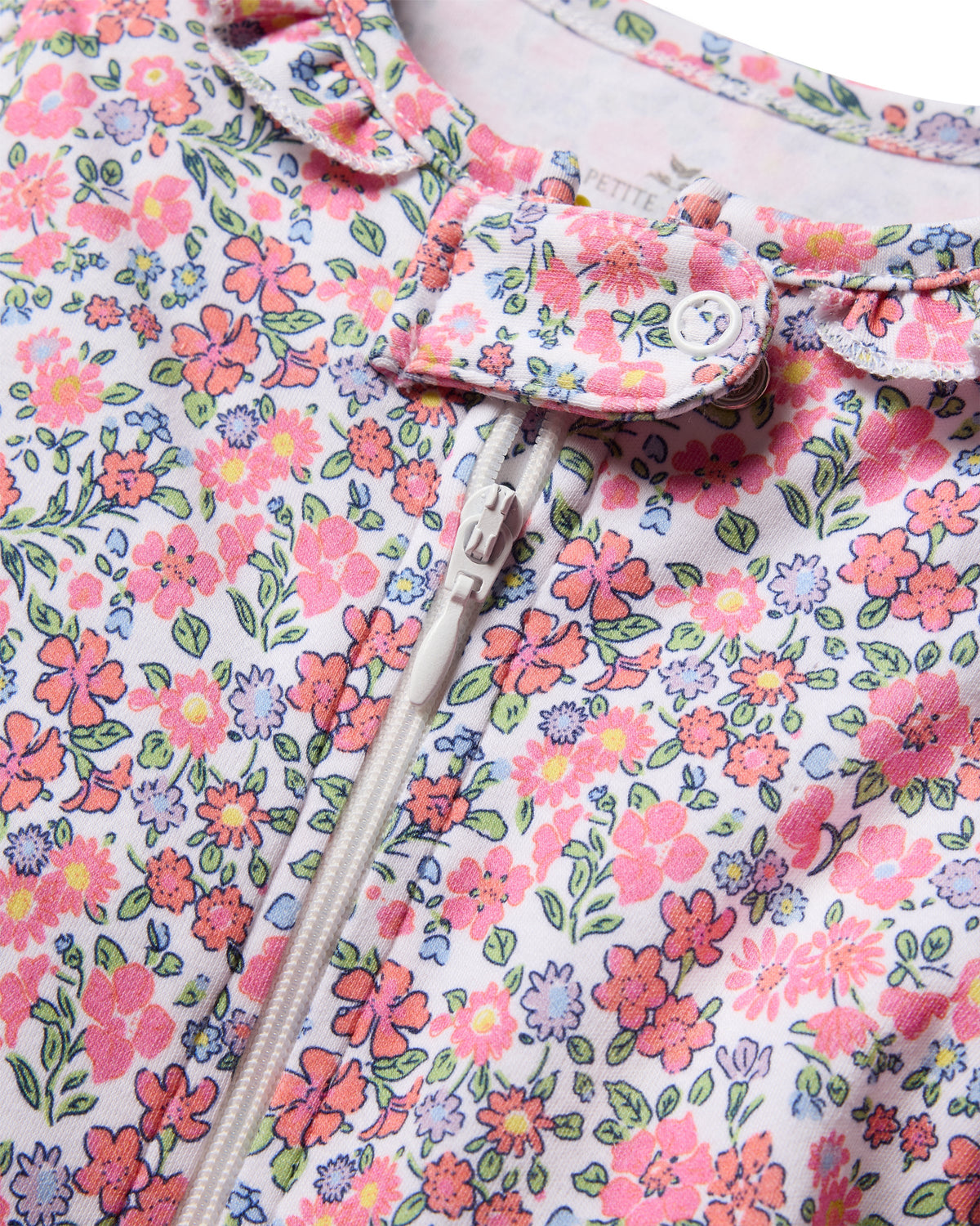 Close up of Baby’s Pima Romper in Fleurs de Rose showcasing floral print, snap buttons, and zipper on white fabric