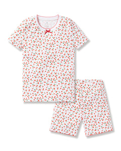 The Petite Plume Kids Pima Snug Fit Short Set in Cherry Orchard features a luxurious Pima Cotton design with a white base, playful red strawberry and green leaf pattern, stylish silhouette, red bow at the neckline, and matching red trim on the short-sleeved top and shorts.