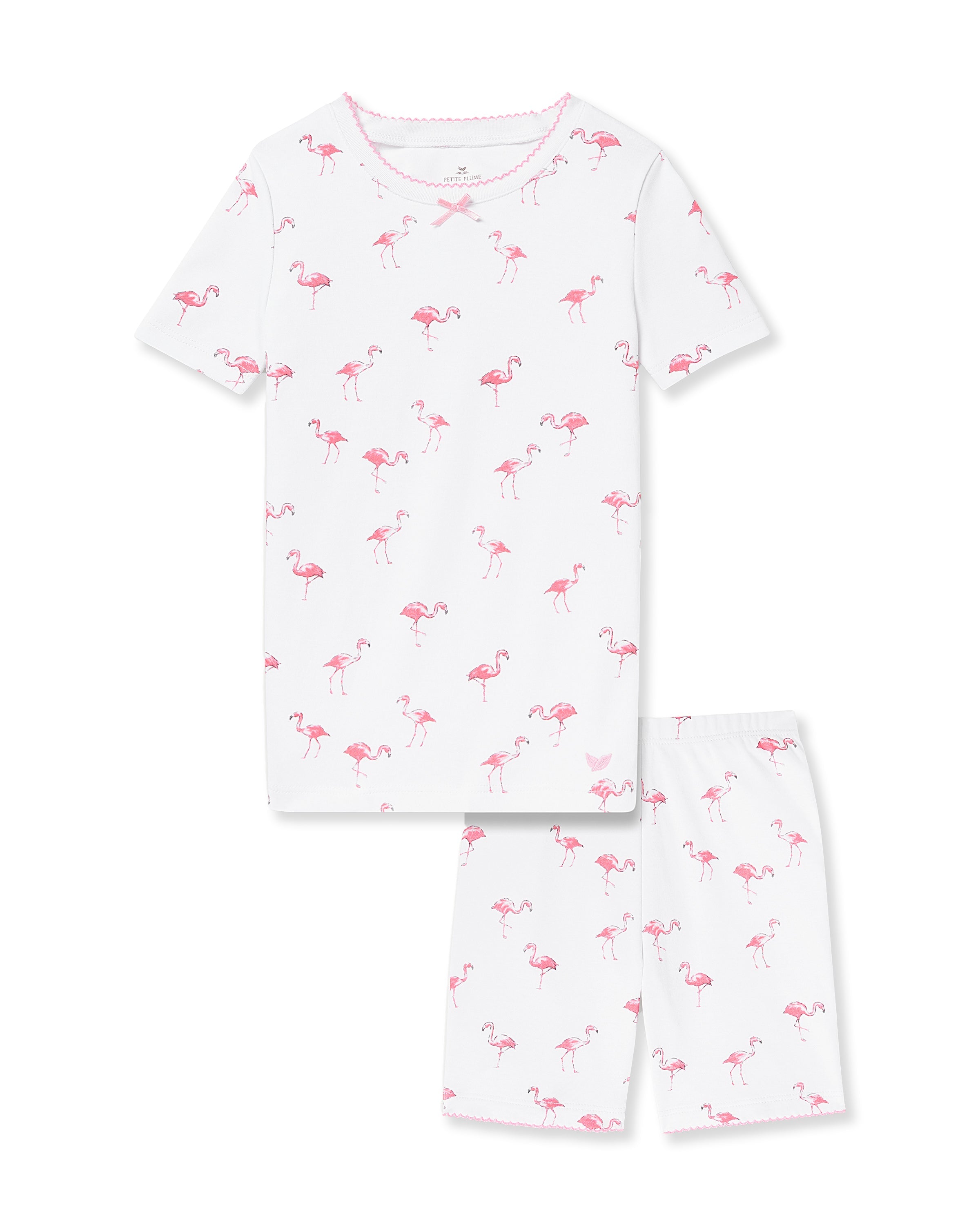 The Kids Pima Snug Fit Short Set in Flamingo by Petite Plume features a white, durable Pima cotton pajama set with a short-sleeved top and shorts, adorned with playful pink flamingos, ensuring comfort for little dreamers.