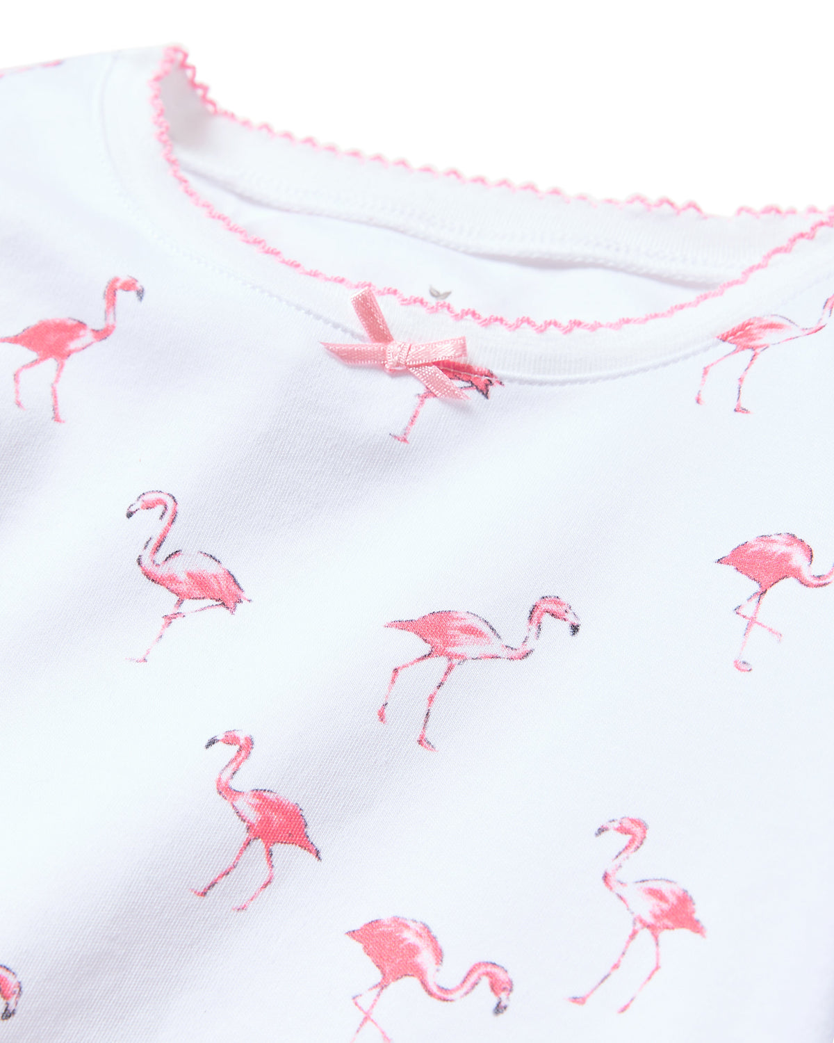 The Kids Pima Snug Fit Short Set in Flamingo by Petite Plume features white Pima cotton fabric adorned with pink flamingos, a neckline with matching pink scalloped trim, and a small bow. Its part of a stylish, simple family sleepwear collection.
