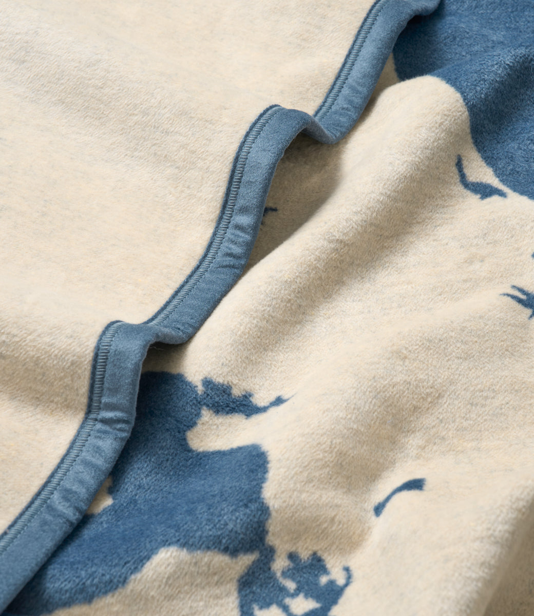 Cream and blue wool blanket with map design and blue binding edge detail.
