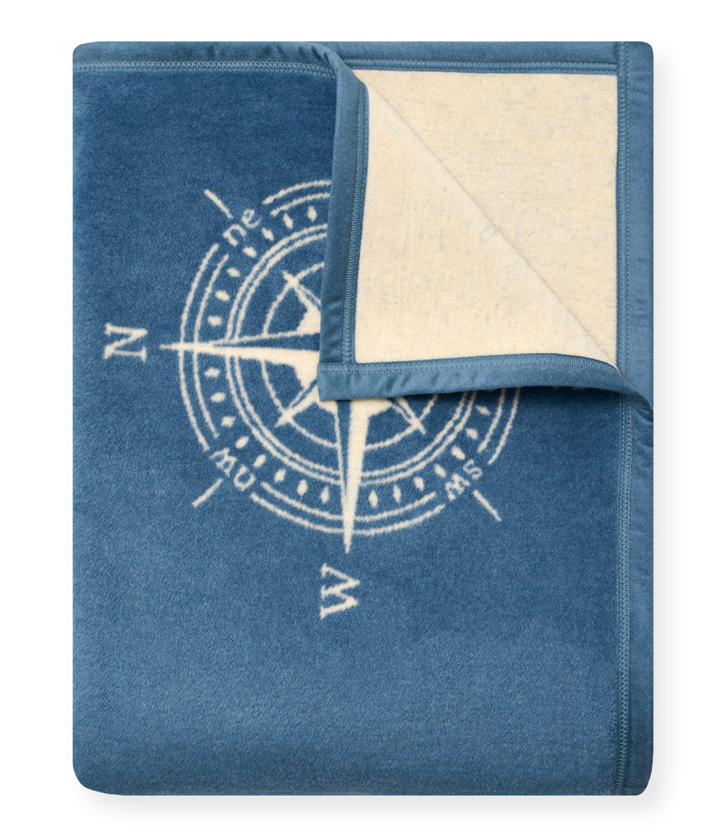 Blue blanket with cream-colored reverse side and compass rose design printed in light blue.