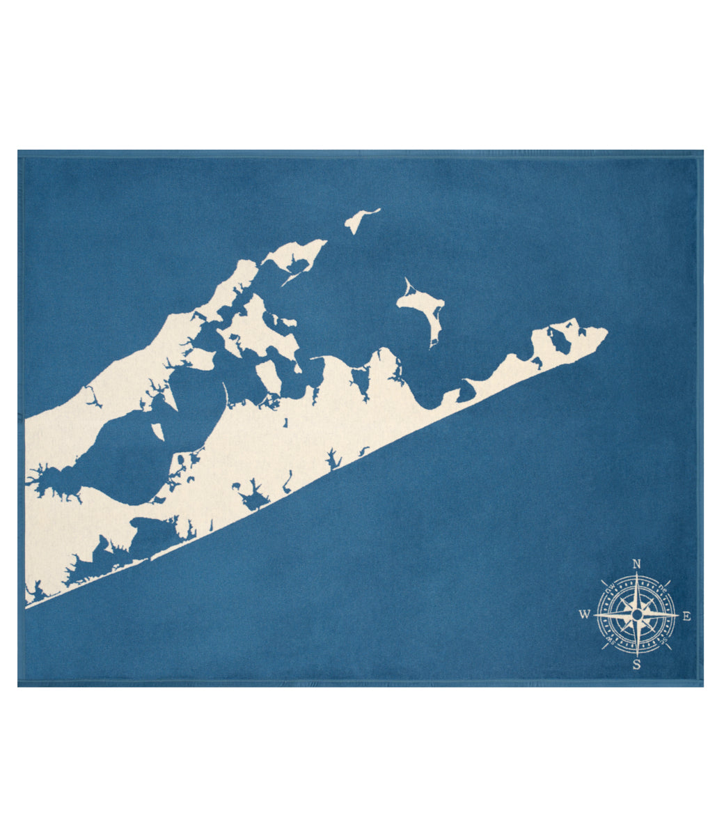 Blue blanket with cream-colored Hamptons map and compass rose design.