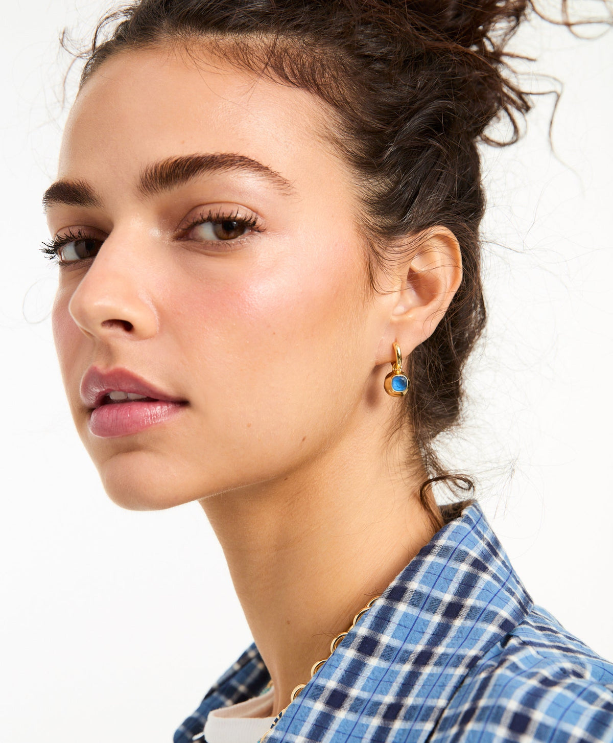 Close-up of The Marino Drop Earrings in Navy showcasing a navy glass stone and gold-tone mini hoop on a model