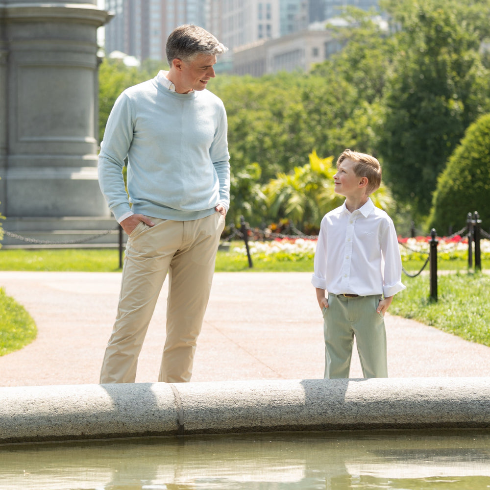 Front view of Bradford trousers on a boy showcasing sage green Hanover herringbone fabric and elastic back waist in a park