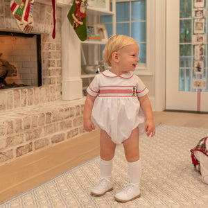 White baby boy holiday bubble with red toy soldier smocking and Peter Pan collar, Henry Duvall's Charlie Bubble in cotton poplin for Christmas celebrations
