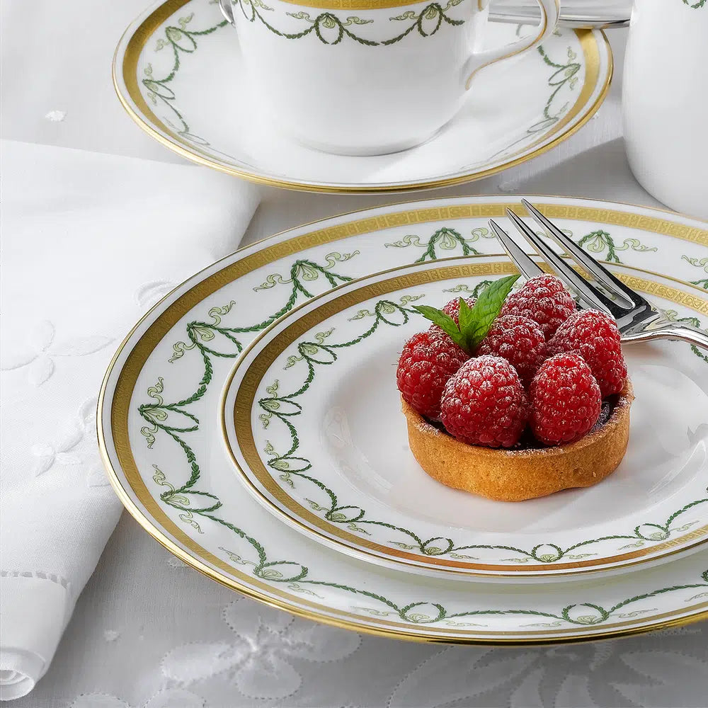 Angled close-up of Titanic Dinner Plate showcasing green garland pattern and gold rim on white bone china with a raspberry tart
