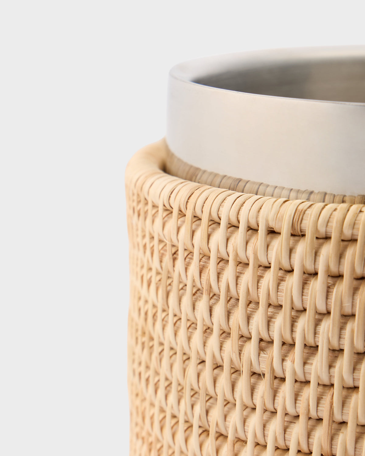 Close-up of Woven Sabbia wine cooler showcasing handwoven rattan exterior and stainless steel insert on light gray background