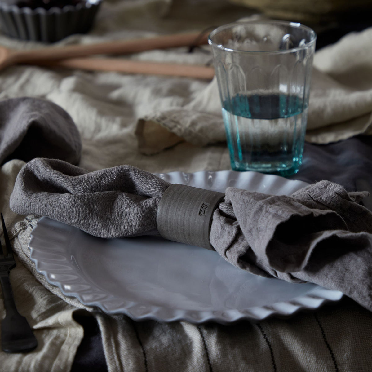 Close-up of Maria Collection Napkins in Dusk Grey, Set of 4 showcasing washed linen texture on a white plate with glass