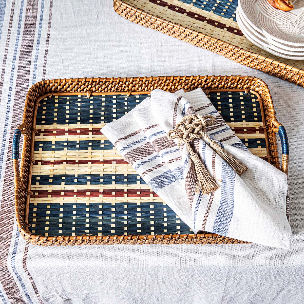 Top view of Danish Stripe 18 inch Tray in Navy showcasing handwoven natural cane wood and navy stripes with a napkin and dishes